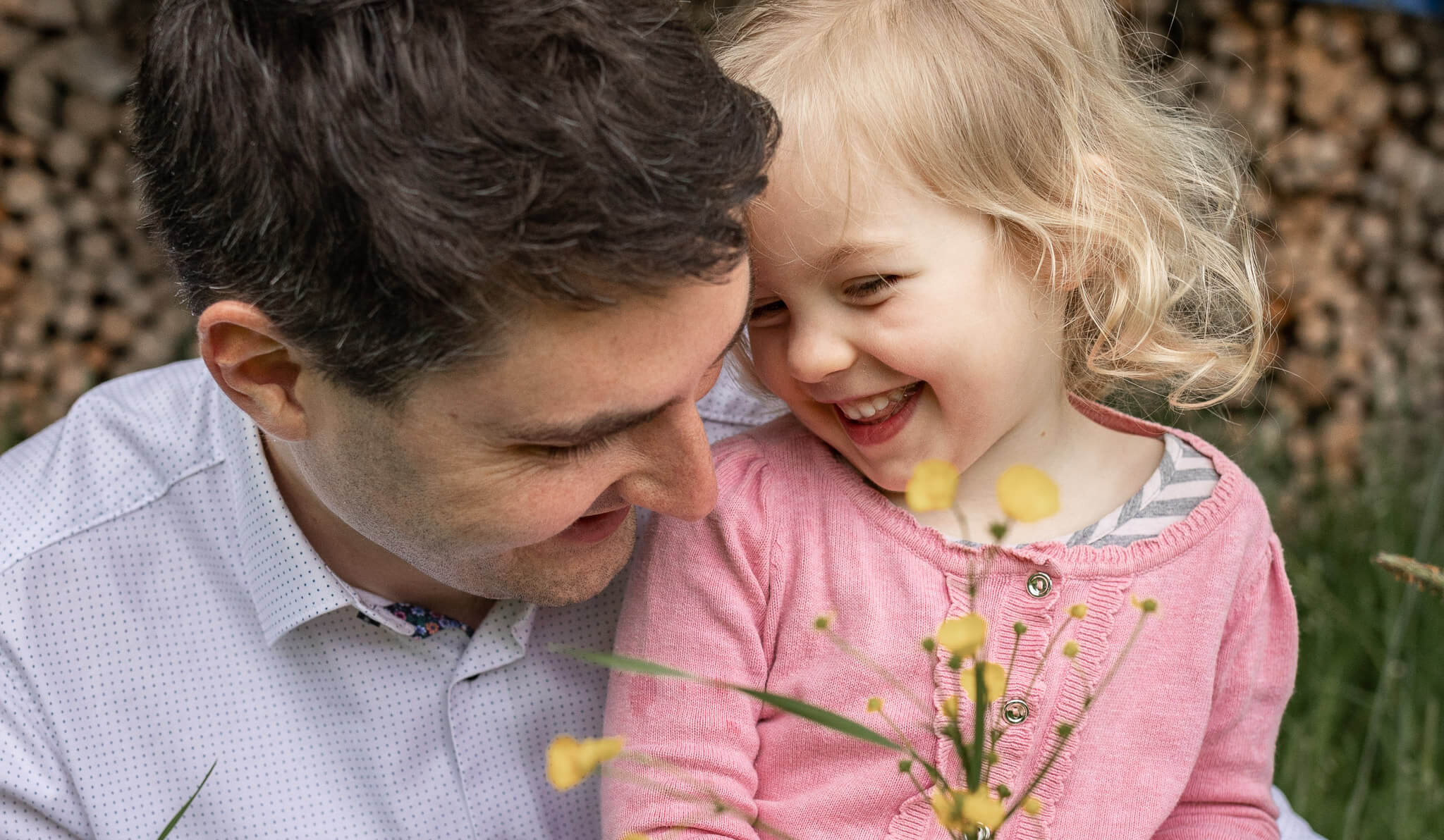 Ein Vater pflückt zusammen mit seiner Tochter Blumen, sie lachen.